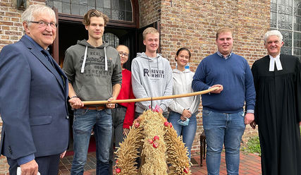 Das Team der Hohenhorster Landjugend trägt die Erntekrone in die Kirche, eingerahmt von Bürgermeister Peter Bröker und Pastor Andreas-M. Petersen - Copyright: Andreas-M. Petersen